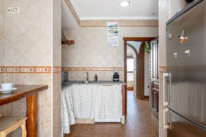 A kitchen with a refrigerator, sink, and wooden table. - Villa Canijo Barbate – Beach House with Private Terrace (Barbate)