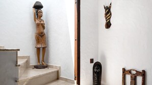 Eine Treppe mit einer Holzstatue auf der Zwischenebene, einem geschnitzten Holzhead an der Wand und einem Holzstuhl.