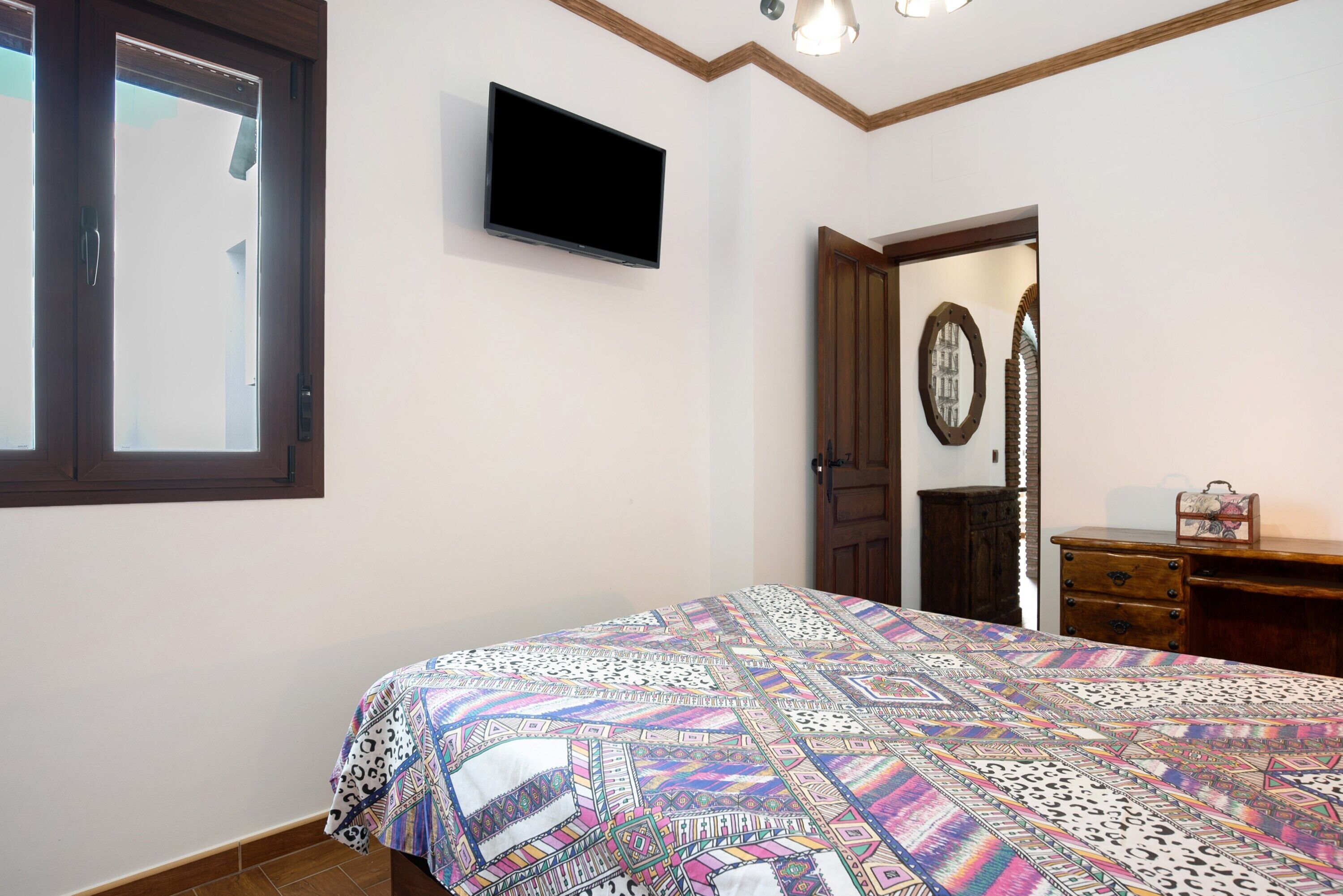 Ein Schlafzimmer mit einem Bett, einem Fernseher, einem Kleiderschrank und einem Spiegel.