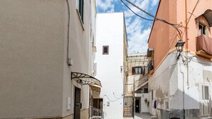 Uma rua estreita com edifícios de ambos os lados, uma varanda visível e uma pequena entrada.
