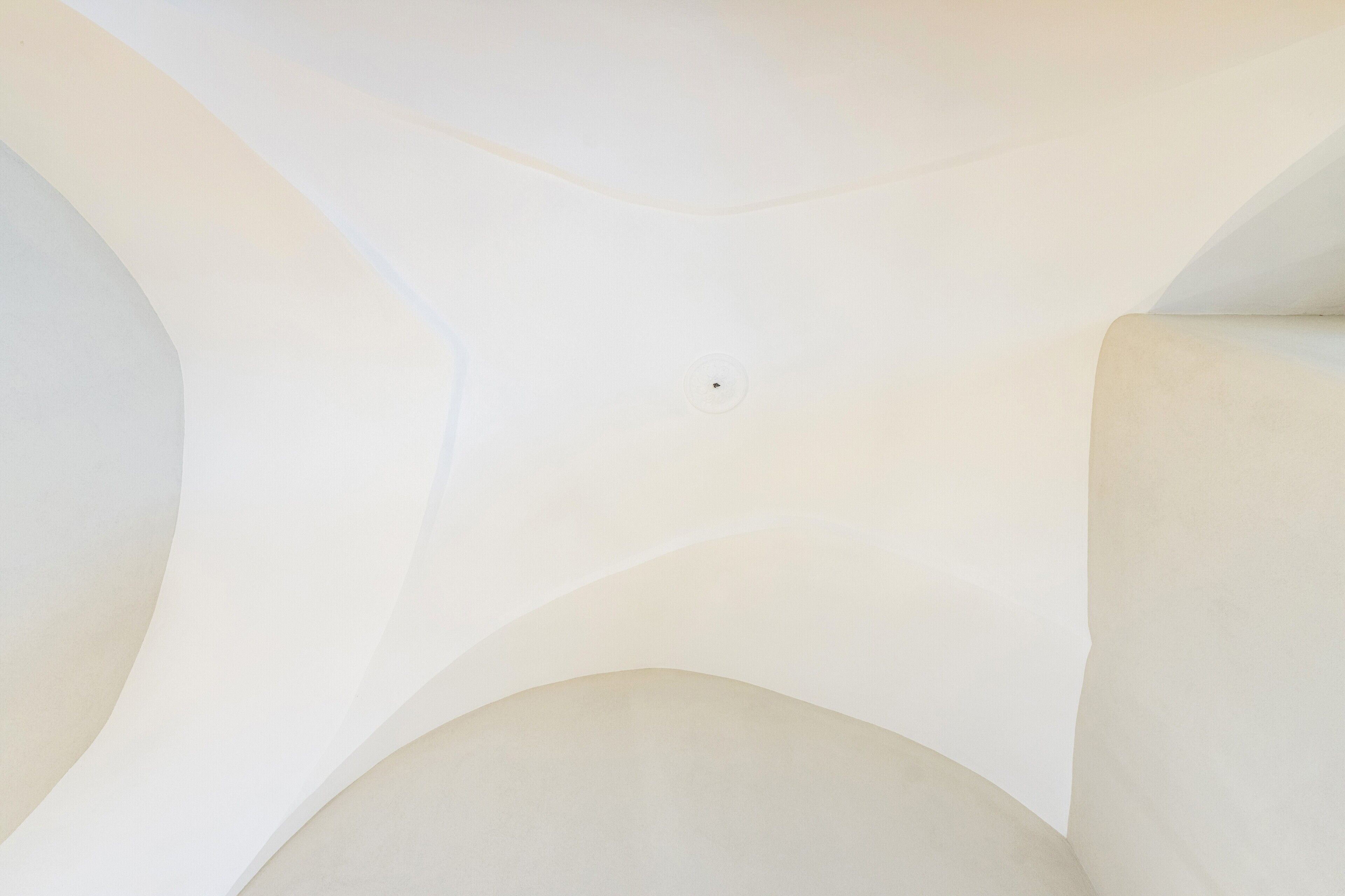 Un plafond doté d’un luminaire central et d’éléments architecturaux aux lignes courbes.