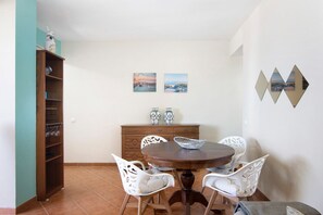 Un coin repas avec une table ronde, des chaises blanches, un buffet en bois et deux tableaux encadrés au mur.