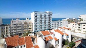 Un hôtel doté d’une terrasse sur le toit, de plusieurs balcons et offrant une vue sur la mer.