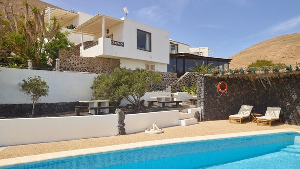 A modern building with a pool, outdoor seating, and a lifebuoy.