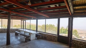 An open-air room with a stone bench, large windows, and a view of the landscape.
