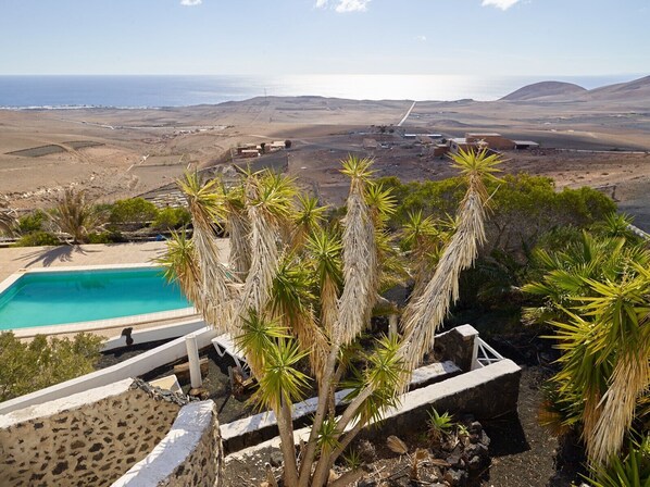 A pool with a view of the ocean and hills.