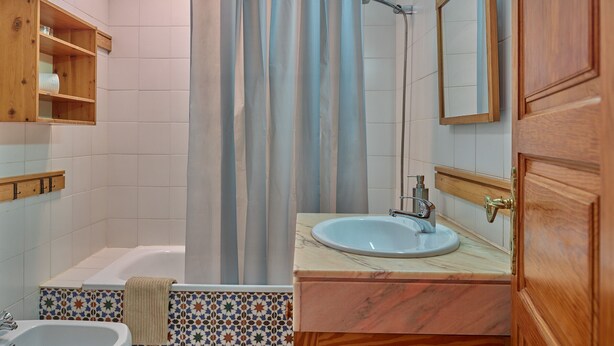 Une salle de bain avec une baignoire, un lavabo, un rideau de douche et un miroir.