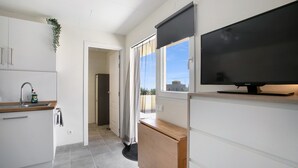 A modern kitchen with a sink, cabinets, a wooden countertop, a television, and a view through a window. - Vacation Apartment 'Fewo Arafo' with Sea View, Private Terrace and Wi-Fi (Güímar)