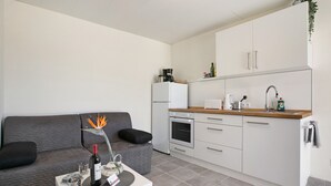 A compact living space with a kitchenette, a grey sofa, a small dining table, and a decorative plant. - Vacation Apartment 'Fewo Arafo' with Sea View, Private Terrace and Wi-Fi (Güímar)