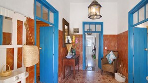 A hallway with blue doors, a hanging basket, a wicker chair with a cushion, and a hanging lantern. - Country House 'Quinta Da Ilda' with Sea View, Wi-Fi and Air Conditioning (Loulé)