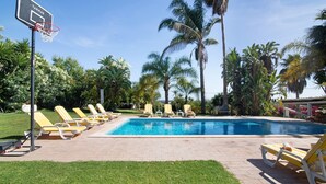 A swimming pool with lounge chairs, palm trees, and a basketball hoop. - Country House 'Quinta Da Ilda' with Sea View, Wi-Fi and Air Conditioning (Loulé)
