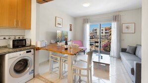 Une cuisine compacte équipée d’un lave-linge, d’un four à micro-ondes et d’un coin repas avec une table et des chaises.