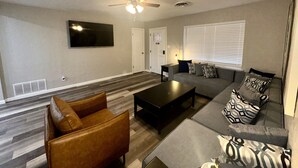 Una sala de estar con un sofá, una mesa de centro y un televisor montado en la pared.