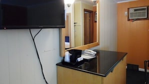 A hotel room with a flat-screen TV mounted on the wall, a wooden counter with a telephone, and a mirror reflecting the room. - Room with Two Double beds Lake George (Lake George)