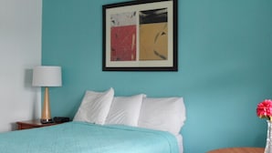 A bedroom with a bed, a nightstand, a lamp, a framed abstract painting, and a small table with a vase of flowers. - Room with Two Double beds Lake George (Lake George)