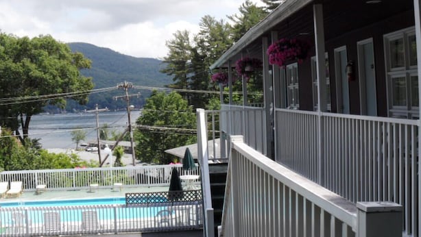 A building with a balcony overlooking a pool and a lake, surrounded by trees and mountains. - Room with Two Double beds Lake George (Lake George)