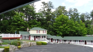 A motel with multiple rooms, a covered parking area, and a natural forest backdrop. - Room with Two Double beds Lake George (Lake George)