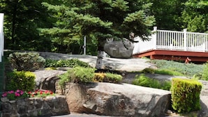 A landscaped garden with large rocks, a white fence, and a red building in the background. - Room with Two Double beds Lake George (Lake George)