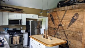 Una cocina con gabinetes blancos, electrodomésticos de acero inoxidable, una isla de madera y un ventilador de techo.