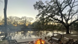 Un parque con una fogata, bancos y un lago.