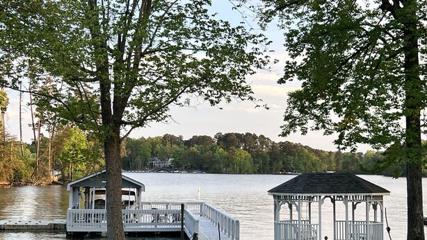 A lakeside gazebo with a dock extending into the water, surrounded by trees and a grassy area. - Dock Holiday - beautiful views on Badin Lake.  Updated kitchen & game room (New London)