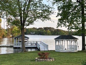 A lakeside gazebo with a dock extending into the water, surrounded by trees and a grassy area. - Dock Holiday - beautiful views on Badin Lake. Updated kitchen & game room (New London)