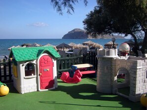 A children's play area with a small house, a pink slide, and a castle structure.