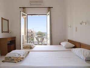 A hotel room with a bed, a bedside table, a mirror, a window, and an open balcony door. - Despina (Katerini)