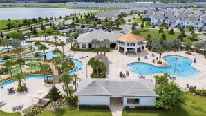 Un resort con varias piscinas, un edificio central espacioso y un lago al fondo.