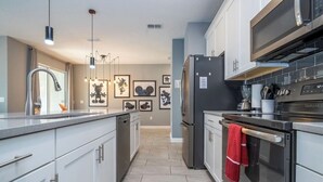 Una cocina moderna con electrodomésticos de acero inoxidable, una isla central y obras de arte en las paredes.