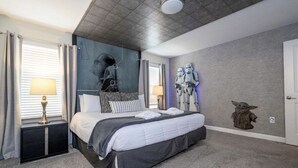 Un dormitorio con una cama, mesitas de noche, un mural y decoración temática de Star Wars.