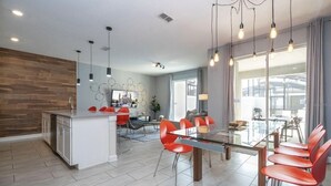 Una cocina moderna con una isla central, sillas rojas y una mesa de comedor.