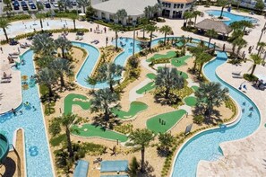 A pool area with multiple water features, palm trees, and lounge areas.