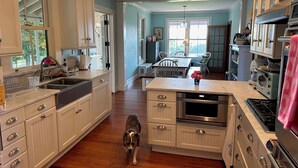 Une cuisine spacieuse avec des meubles blancs, un plancher en bois et un coin repas comprenant une table et des chaises.