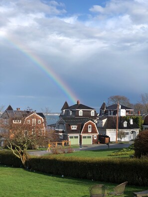 A residential area with houses, a grassy lawn, and a rainbow.