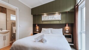 A hotel room with a bed, a nightstand, a lamp, a window with curtains, and a bathroom visible through an open door. - Willow Lodge VIP Hot Tub and Pet Friendly (Bridgnorth)