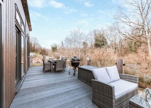 A wooden deck with wicker furniture, a barbecue grill, and a view of a wooded area. - Willow Lodge VIP Hot Tub and Pet Friendly (Bridgnorth)