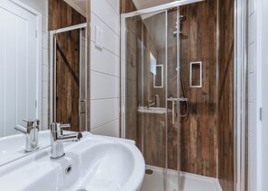 A modern bathroom with a glass-enclosed shower, a white sink, and wooden paneling on the walls. - Willow Lodge VIP Hot Tub and Pet Friendly (Bridgnorth)