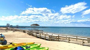 Una playa con kayaks, un muelle de madera y un pequeño refugio.