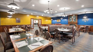 Un restaurante con varias zonas de comedor, incluyendo cabinas y mesas, suelo alfombrado e iluminación en el techo.