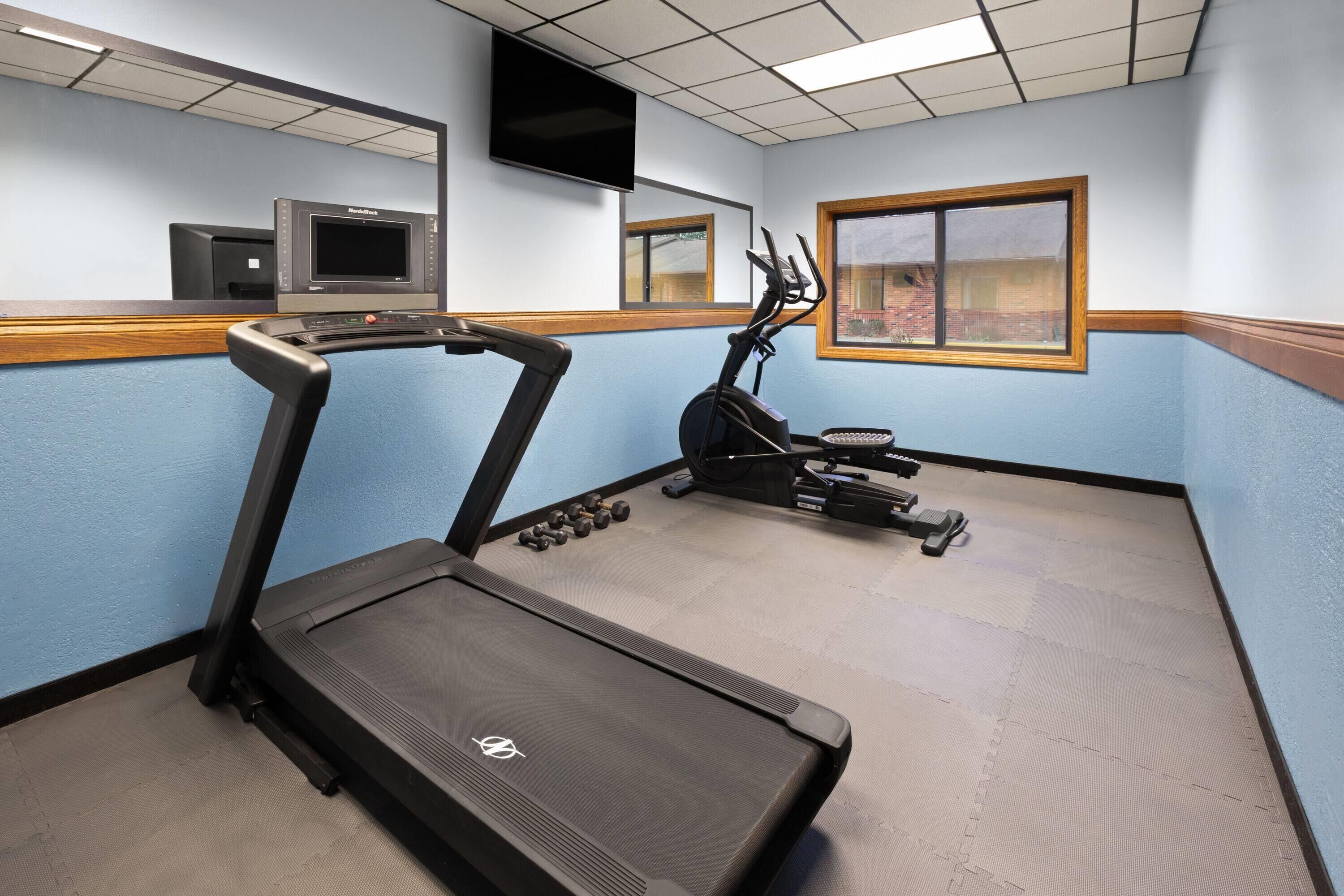 Un gimnasio con cinta de correr, elíptica y pesas.
