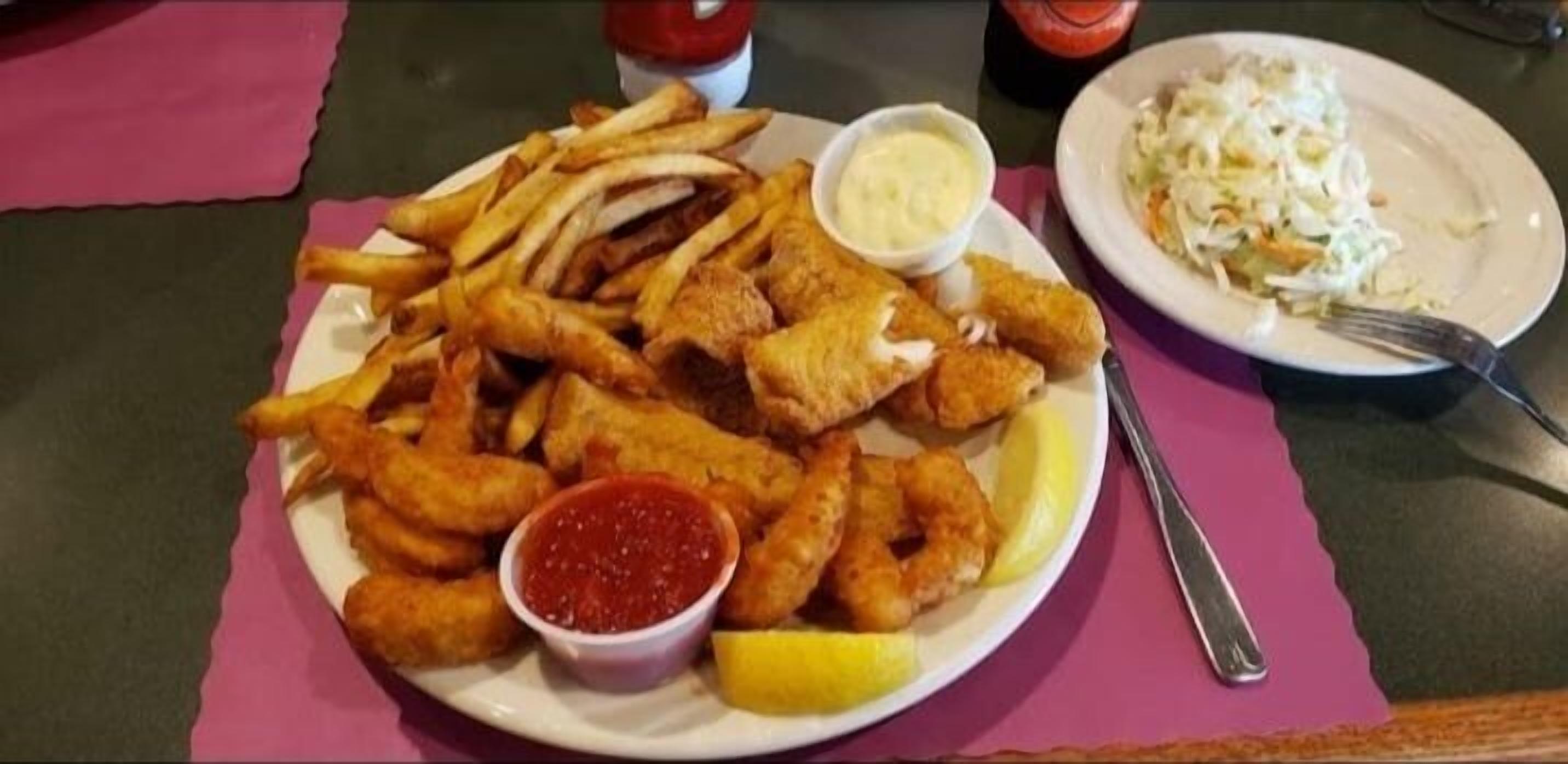 Ein Teller Fish and Chips mit Zitronenspalten und zwei Soßen.