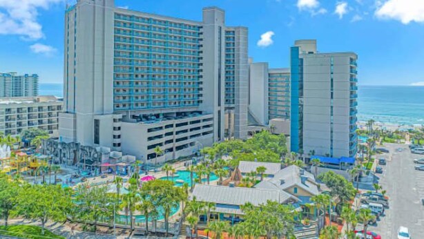 A large hotel with multiple floors, a pool area, and a view of the ocean. - Sand Dunes 2451 (Myrtle Beach)