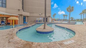 A swimming pool area with a palm tree, lounge chairs, and a building in the background. - Sand Dunes 2451 (Myrtle Beach)