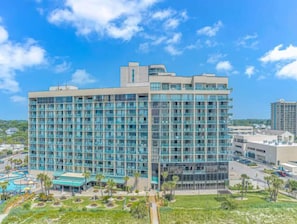 A multi-story hotel with a modern design, featuring a large pool area and a well-maintained landscape.