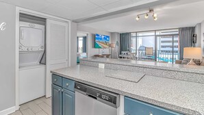 A modern kitchen with granite countertops, a dishwasher, and a view of the pool area. - Sand Dunes 2451 (Myrtle Beach)