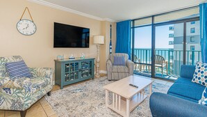 Una sala de estar con sofá, sillón, mesa de centro, televisor y aparador.