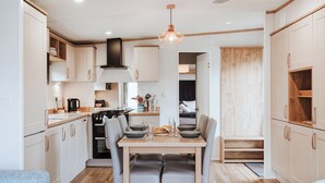 A compact kitchen with a dining area, wooden flooring, and a pendant light.