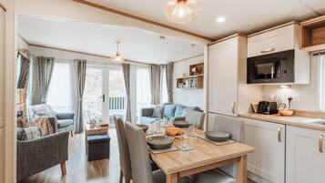 A modern kitchen with a wooden table, chairs, and a microwave.