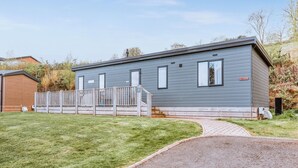 A single-story mobile home with a front porch, a small attached garage, and a paved driveway.